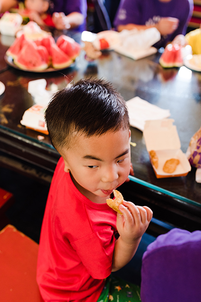 boy enjoying chicken nuggets with plate full of watermelon in background