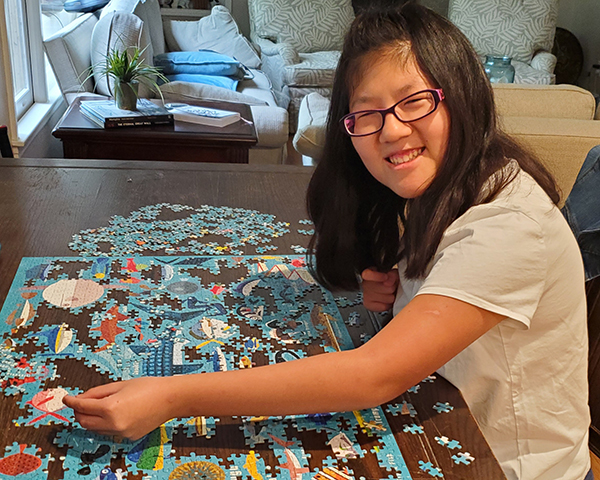 zoey is happily working a large puzzle