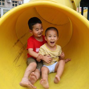 two boys laughing on slide