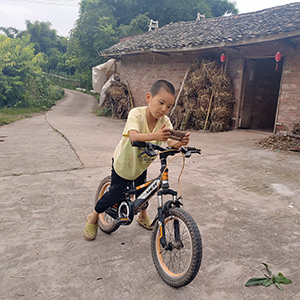 YiMan on his bicycle in his village